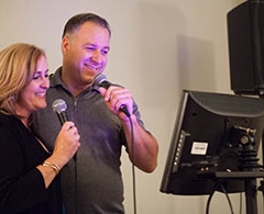 Man and woman sing karaoke with screen.