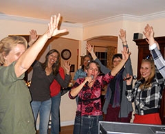 Group of party people doing karaoke in a living room.