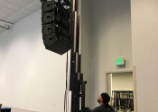 Speaker line array being hoisted into air by technician.