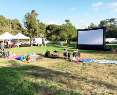 an inflatable movie screen setup in a park in los angeles at sunset.