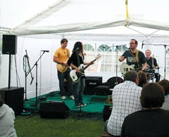 Band plays on stage under tent with iPlay sound system setup.
