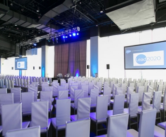 all white room setup for corporate meeting with projection screens.