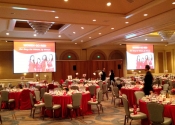 Ballroom set for lunch with two large screens displaying images.