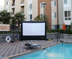 Inflatable outdoor screen, projector and sound system set up by pool.